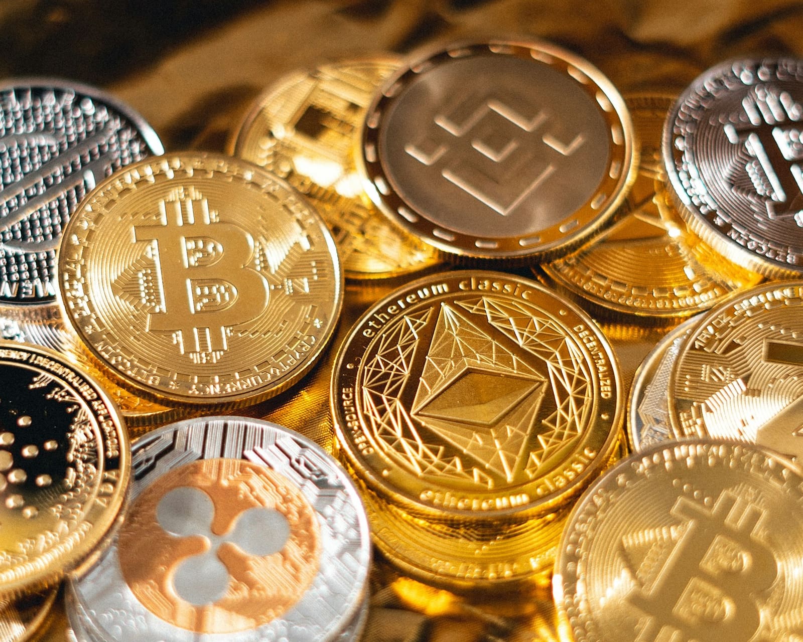 Gold and silver cryptocurrency coins, including Bitcoin, Ethereum and Litecoin, resting on gold foil